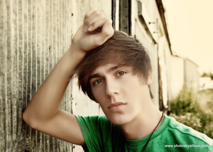 high_school_senior_boy_leaning_metal_shed.jpg